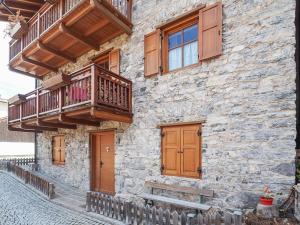 een stenen gebouw met een balkon en houten deuren bij Casa Riccardo in Soraga