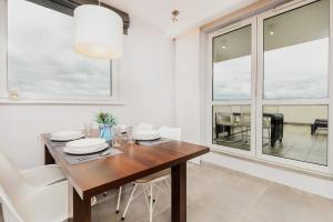 a dining room with a wooden table and white chairs at City and Sea View Apartments by Renters in Gdańsk