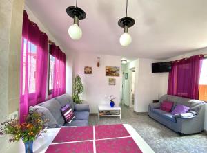 salon z fioletowymi zasłonami i kanapą w obiekcie Home2Book Relax Apartment Buenavista w mieście Buenavista del Norte