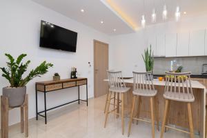 a kitchen with a table and chairs and a tv on the wall at Aphrodite Studios & Suites in Alykes