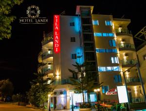 a hotel building with a neon sign in front of it at Hotel Landi in Ksamil