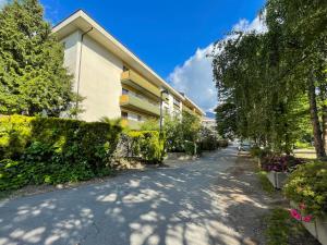a building with trees and bushes next to a street at Apartment Manuela in Merano