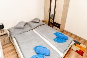 een bed met blauwe kussens in een kamer bij Lili Apartman in Harkány