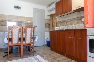 uma cozinha com armários de madeira e uma mesa e cadeiras em Lili Apartman em Harkány