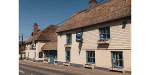 una fila de casas con techos de paja en una calle en The Blue Ball Inn, en Sidmouth