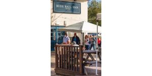 a group of people standing around a table under a white tent at The Blue Ball Inn in Sidmouth