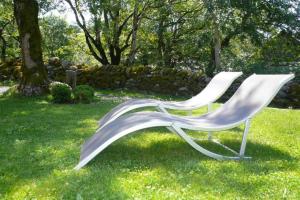 Gite aux Caprices d'Aubrac في لاغيول: كرسي أبيض جالس في العشب في ساحة