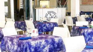 um grupo de mesas e cadeiras brancas com pano de mesa roxo em Petit gourmet em Siderno Marina