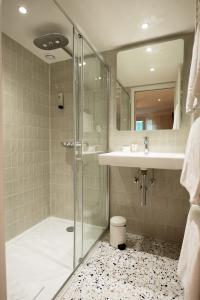 W łazience znajduje się szklana kabina prysznicowa i umywalka. w obiekcie Hôtel Des Batignolles w Paryżu