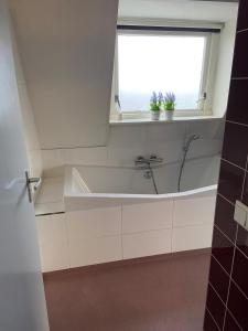 a bathroom with a bath tub and a window at Appartement De Kaai in Sint Annaparochie