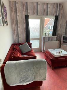 a living room with a red couch and a window at Appartement De Kaai in Sint Annaparochie