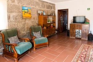 a living room with two chairs and a television at Leira da Cruz Grande in Castelo de Paiva