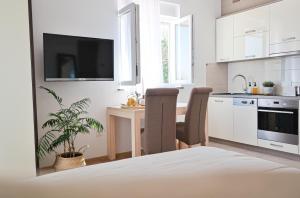 a white kitchen with a table and a tv at KARBONACA APARTMENTS in Fažana