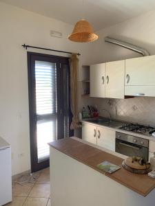cocina con armarios blancos, fogones y ventana en Casa Vacanza Almoraima - Salento -, en Bagnolo del Salento