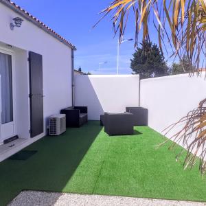 a patio with green grass and a white wall at Logis du Château in Le Château-dʼOléron