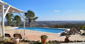 a swimming pool with chairs and a view of the mountains at Quinta O Ninho in Monchique