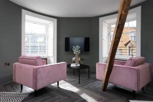a living room with pink chairs and a tv at 29 Queen Street Luxury Flats in Edinburgh