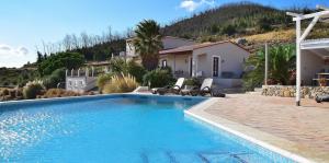 a swimming pool with two chairs and a house at Quinta O Ninho in Monchique