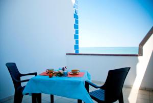 stół z 2 krzesłami i niebieską tkaniną w obiekcie In Riva al Mare B&B w mieście Capo dʼOrlando