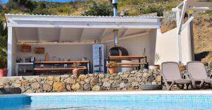 a house with a swimming pool next to a stone wall at Quinta O Ninho Bed & Breakfast in Monchique