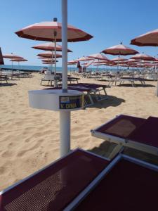 Ein Haufen Tische und Sonnenschirme am Strand in der Unterkunft Hotel Villa Dina in Lido di Jesolo