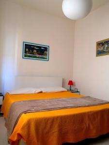 - une chambre avec un lit et une couverture orange dans l'établissement Piccolo B, à Bosa