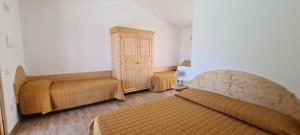 a bedroom with two beds and a wooden cabinet at Azienda Agrituristica La Janna di la Faj in Budoni