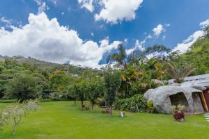 um jardim com árvores e um edifício e uma montanha em Pousada Cantagalo em Itaipava