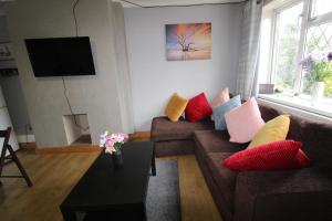 a living room with a brown couch with colorful pillows at Holland House in Unstone