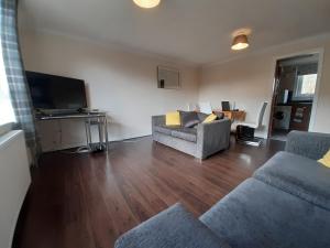 sala de estar con sofá y TV en Carvetii - Stuart House - 1st floor flat sleeps up to 8, en Falkirk