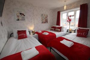 um quarto com duas camas com lençóis vermelhos e brancos em Holland House em Unstone