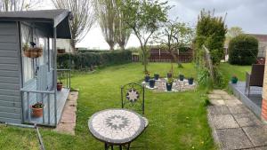 un patio con una mesa y un jardín con una casa en Prelude Guesthouse, Brigsley Grimsby, en Grimsby