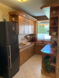 a kitchen with wooden cabinets and a black refrigerator at Relax Apartman in Hajdúszoboszló