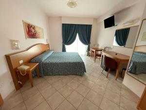 ロゼート・デッリ・アブルッツィにあるローゼズ ホテルのベッドルーム1室(ベッド1台、テーブル、デスク付)