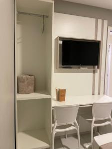 a room with a desk with a tv and two chairs at Hotel Estação in Barueri