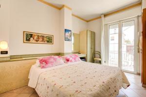 um quarto com uma cama com lençóis cor-de-rosa e uma janela em Hotel Residence Charles em Rimini