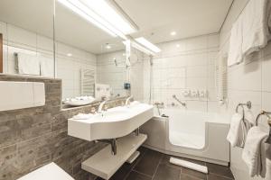 a white bathroom with a sink and a tub at Albana Real Boutique Hotel - Restaurants & Spa in Zermatt