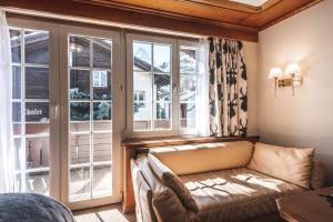 a living room with a couch in front of a window at Albana Real Boutique Hotel - Restaurants & Spa in Zermatt
