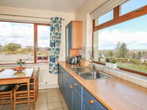 uma cozinha com um lavatório, uma mesa e janelas em Ard na Gréine em Kilrean