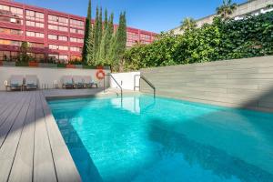 uma piscina com água azul em frente a um edifício em Occidental Sevilla Viapol em Sevilha