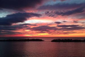 una puesta de sol sobre el océano con rocas en el agua en Bilocale Fronte Mare, en Marina di Pisa