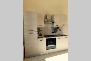 a kitchen with white cabinets and a stove top oven at Bilocale Fronte Mare in Marina di Pisa
