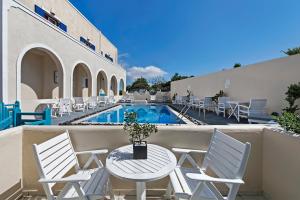 un patio con mesa, sillas y piscina en Alizea Villas & Suites, en Fira
