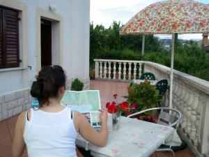 a woman sitting at a table reading a book on a balcony at Apartments Villa Andreja Opatija in Opatija