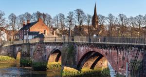 a bridge over a river with a person walking on it at 3 The Gathering Chester Central in Chester