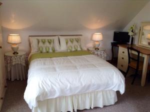a bedroom with a white bed with two tables and two lamps at Glencurrah House B&B in Glenbeigh