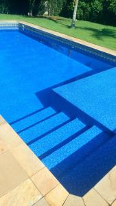 una piscina con agua azul y escaleras en ella en Linda Casa de Campo - Próximo à SP - Wi-Fi grátis, en Bom Jesus dos Perdões