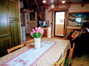 un tavolo con un vaso di fiori rosa sopra di Casa Rainolter a Livigno
