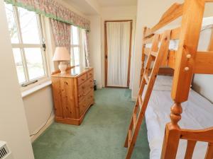 a bedroom with a bunk bed and a desk at Lupin Cottage in Wooler