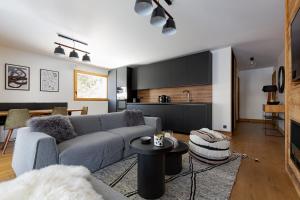 a living room with a couch and a kitchen at Interlude Megève 4 Stars 2BR Parking & Garden in Megève